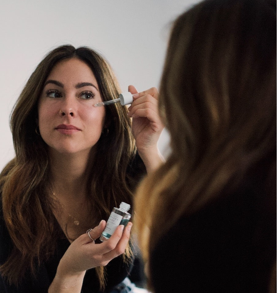 Alt: woman pouring drops of serum on her cheeks