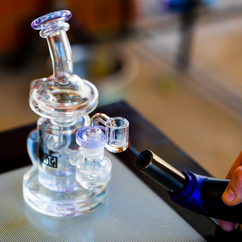 The Dung recycler dab rig in purple being heated up with a jet lighter for dabs