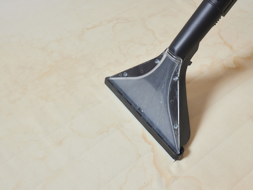 Image of an upholstery attachment being used to clean a stained cusion