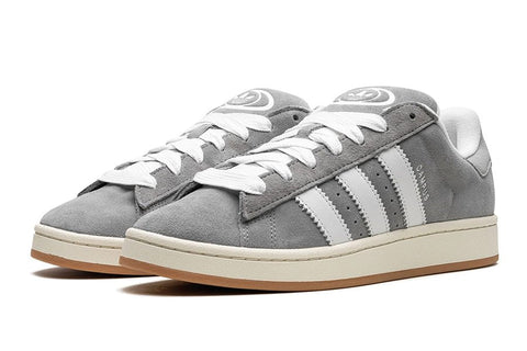 Ein Paar Adidas Campus 00s in Grau. Der Schuh hat ein schlichtes Design mit einem Obermaterial aus Nubukleder und drei weißen Streifen.