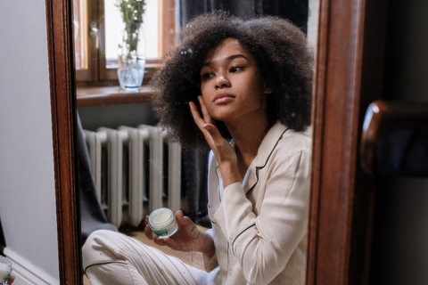 Woman applying lotion on her face