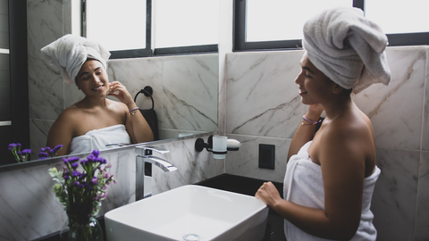 A person admiring their glowing skin in a mirror