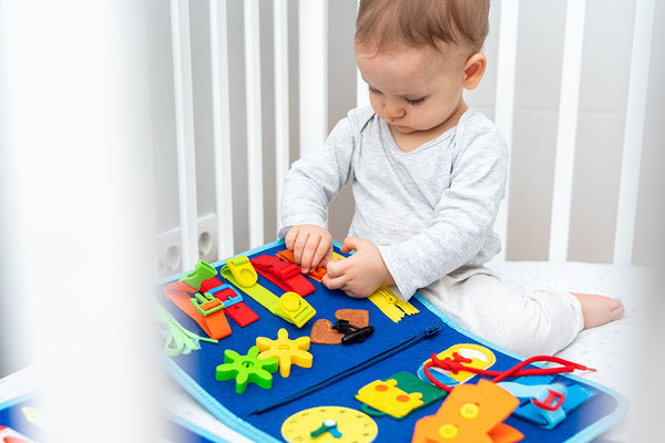 Baby playing with Montessori Busy Book in a crib