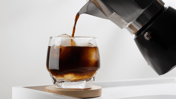 Der Kaffee mit dem Espressokocher ist gekocht und wird nun in ein Glas mit Eiswürfeln gefüllt.