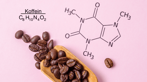 Die chemische Formel von Koffein C8H10N4O2 steht auf rosa Hintergrund, mit einer Kelle voll Kaffeebohnen im Vordergrund.