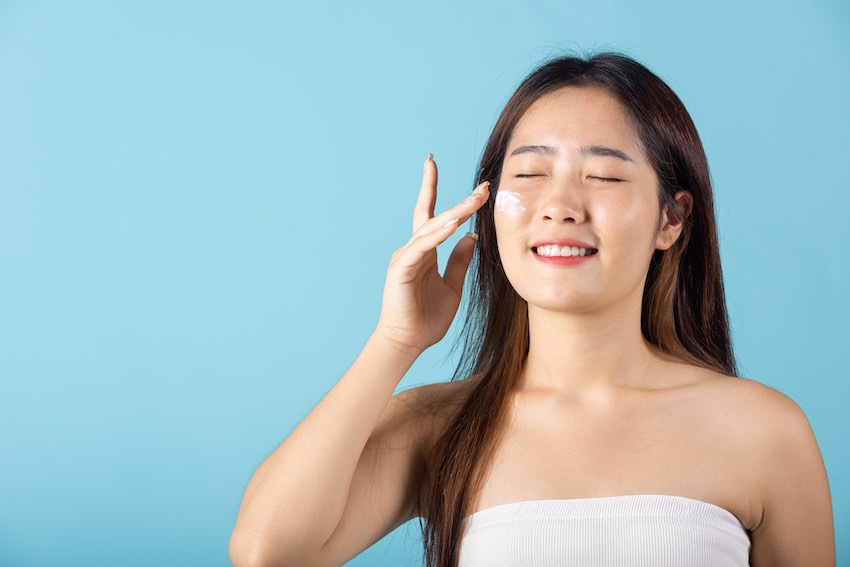 Woman applying moisturiser