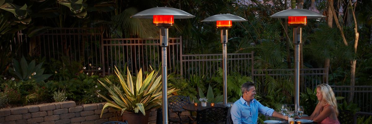 A man and woman sitting at an outdoor table, surrounded by mushroom patio heaters