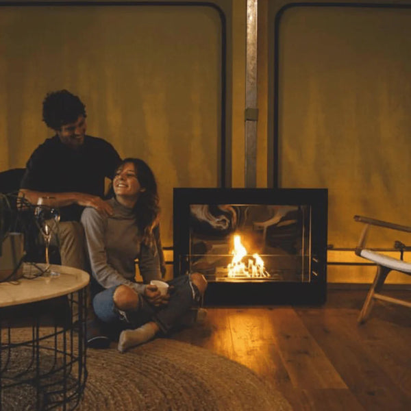 Image of a couple sitting on the floor beside The Bio Flame Rogue 2.0 36-Inch Single Sided Ethanol Fireplace