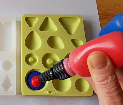 red liquid clay being poured into sculpey mould