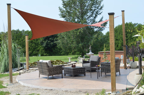 An image of a Shade Sail on a summer day. The Sun Shade is protecting a patio area, contrasting beautifully against the blue sky.