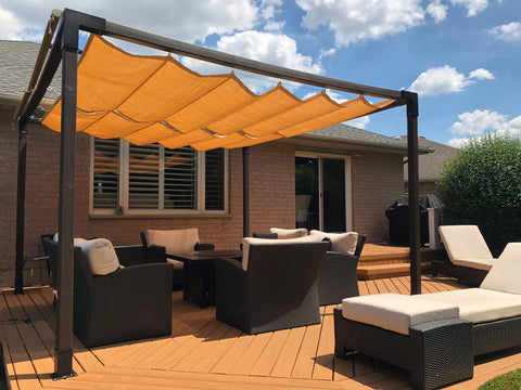 Backyard of a small house featuring an orange pergola retractable over the deck, with a stylish patio set underneath.