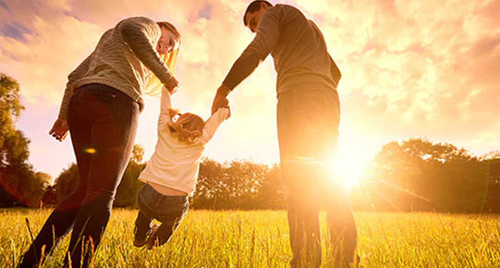 Happy family out in a field while sun is setting