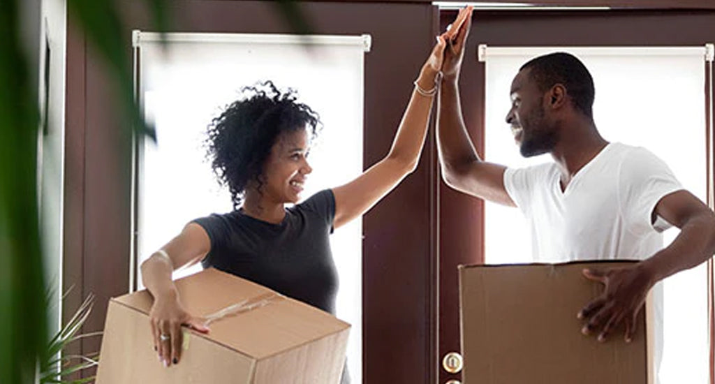 Happy couple holding boxes in their home