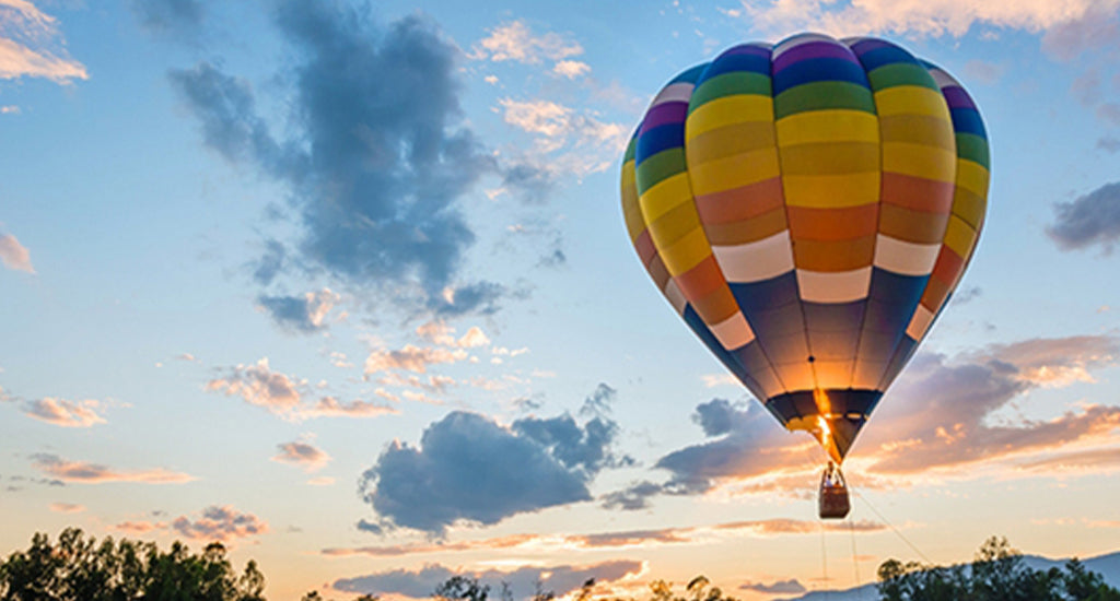 Hot air balloon flying over trees with beautiful landscape