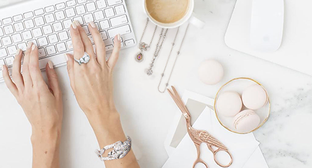 Woman wearing Shimansky jewellery while sitting at her desk, typing on her keyboard