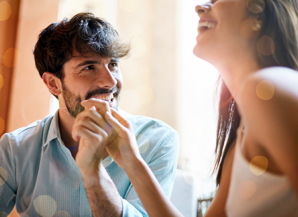 man holding woman's hand looking at her laughing