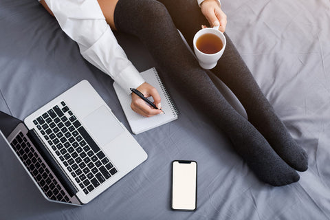 Woman sitting on a bed with a laptop
