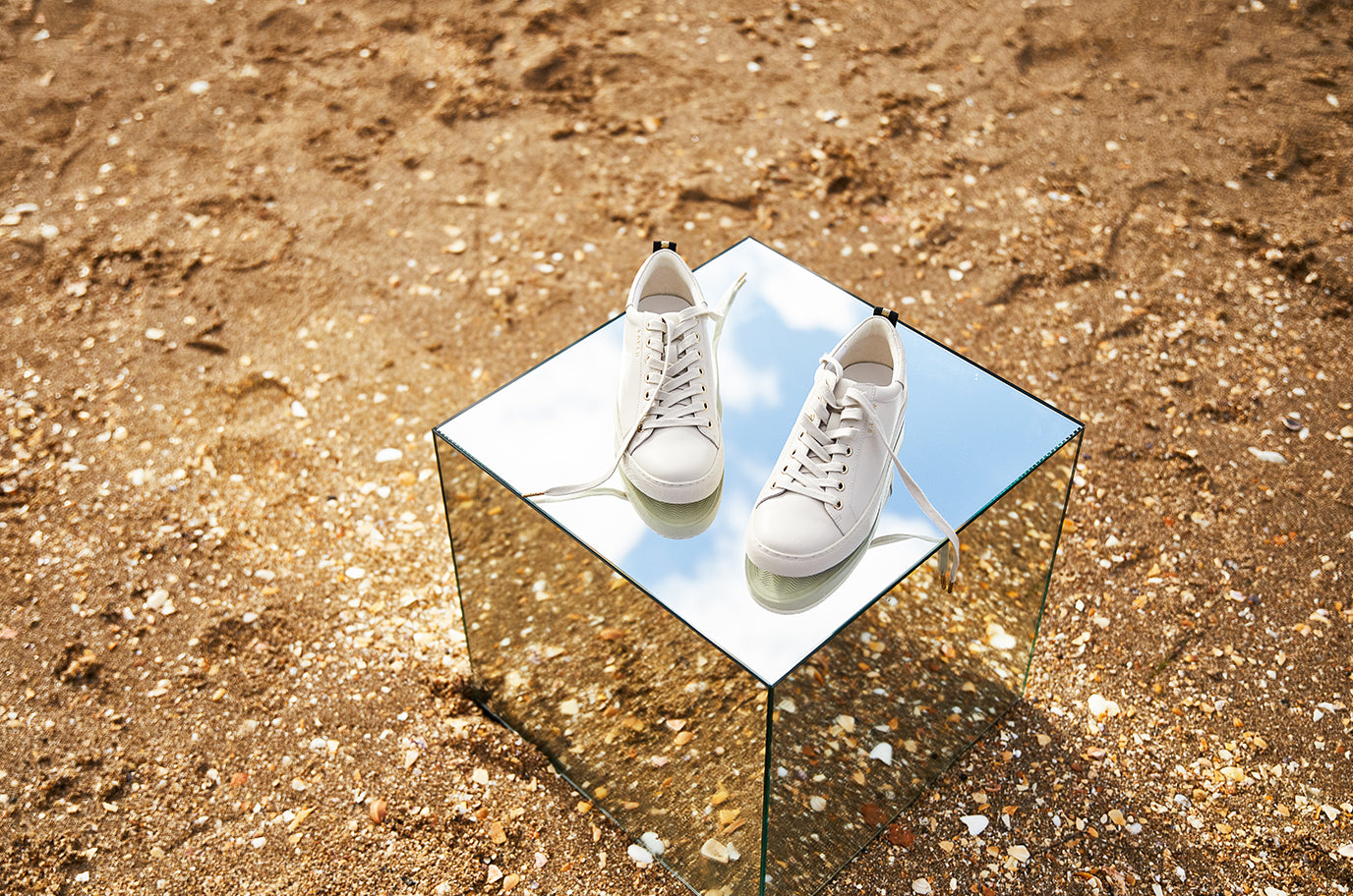 saben leather white sneaker sitting on mirror box in sand