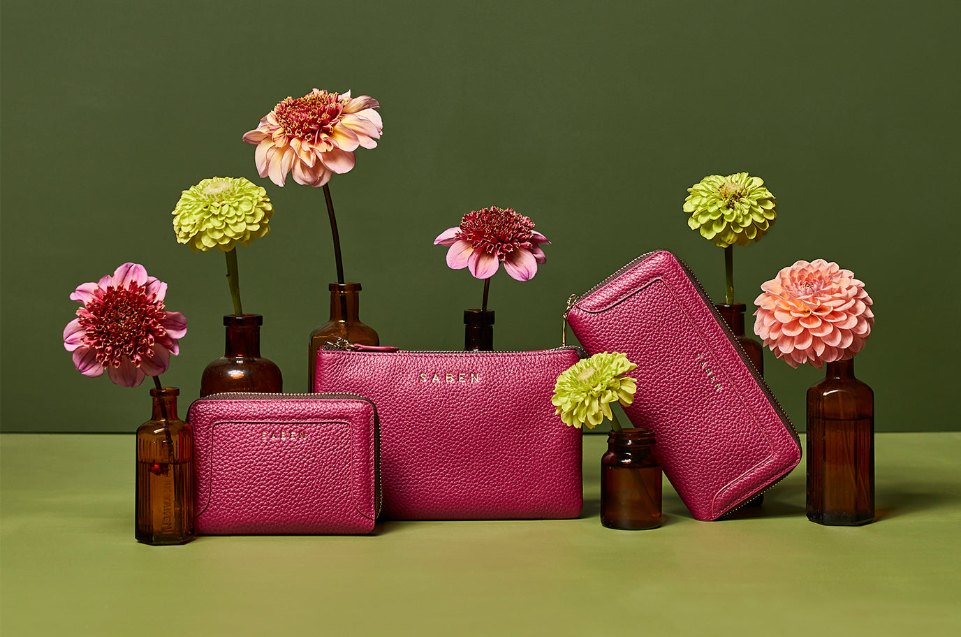 new saben orchid pink leather wallets and handbags sit on green background