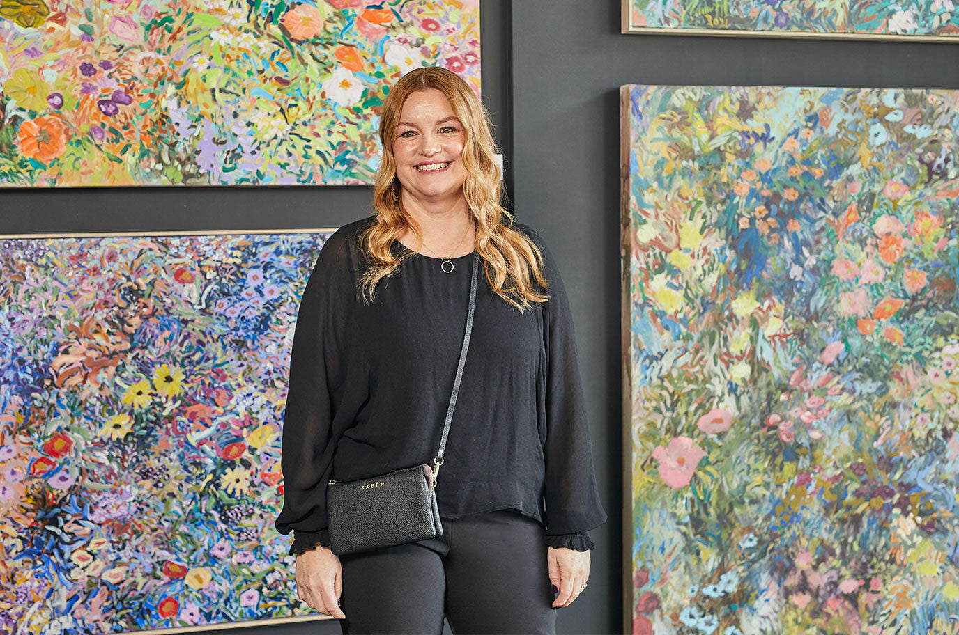 melissa of turua galler wearing saben tilly crossbody black infront of carmel van der hoeven paintings