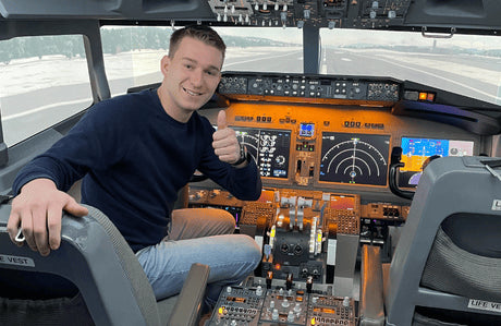 Der Pilot Dustin sitzt im Cockpit eines Boeing 737 Flugsimulators und gibt einen Daumen hoch.