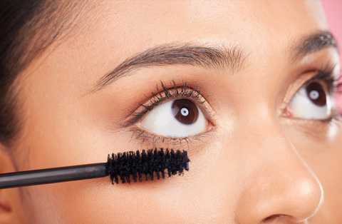 woman with long lashes applying mascara
