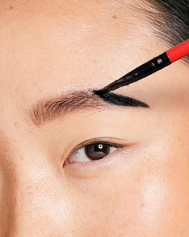 woman applying eyebrow tint with spoolie