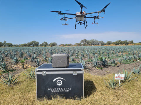 drones para agricultura; caja con el logo de GeoSpetral y con un dron de color gris encima, al fondo se pueden ver plantas y un extenso campo.