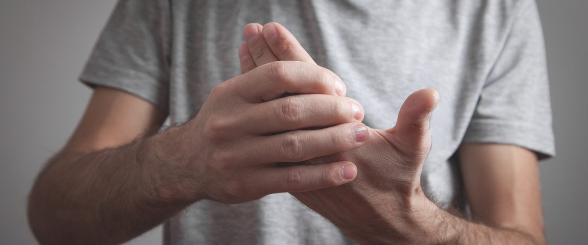 Homme tenant les doigts à cause de la douleur. Les douleurs au doigt et au pouce peuvent être traitées avec un appareil TENS.