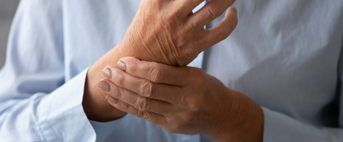 L'homme tient ses poignets à cause de la douleur de la goutte, qui peut être traitée avec un appareil TENS.