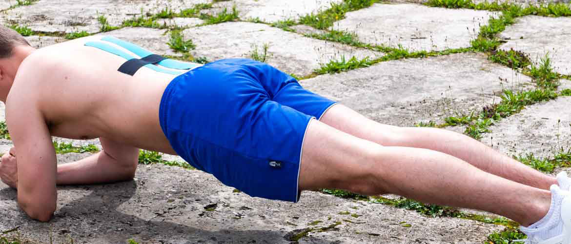 Mann macht sportliche Übungen mit durch Kinesiologie Tape getapten Rücken