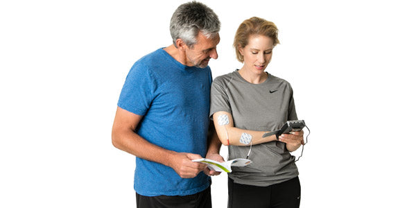 Mann und Frau benutzen das axion TENS Gerät sicher und lesen die Gebrauchsanweisung