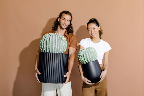 couple holding garden pots with cactus plants