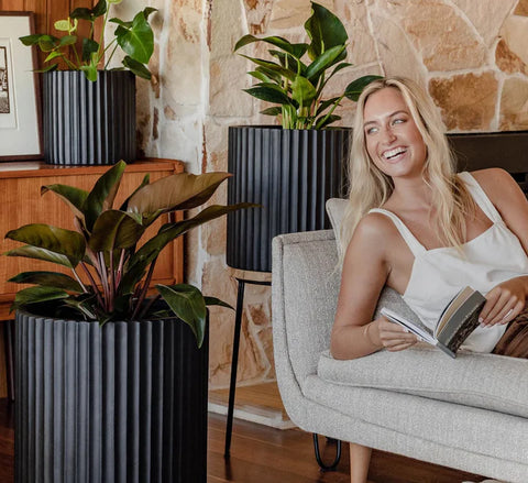 Interior design with Slugg modern indoor plant pots and a woman enjoying her lush greenery in a cozy home setting