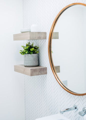 Chic bathroom design with a Slugg concrete plant pot on wooden shelving, adding a touch of greenery next to a round mirror