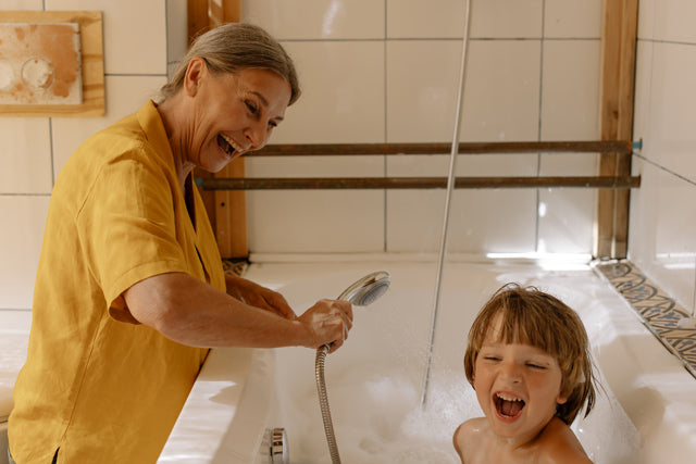 woman playing with boy in bathtub