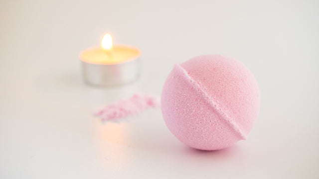 pink bath bomb and lit candle