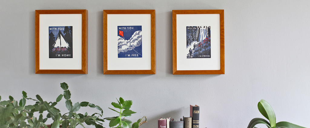 three framed art prints hanging on the wall with christmas cactus fronds in the bottom of the frame