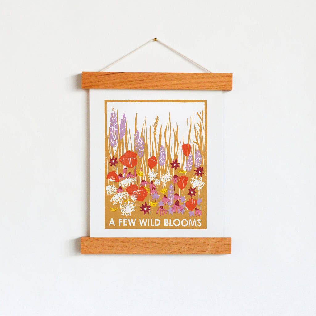 Art print designed using hand-carved woodblocks with a woodcut image of a field of wildflowers with coneflowers, poppies, queen anne's lace and black-eyed susans in ochre, red, lilac, pink and yellow.