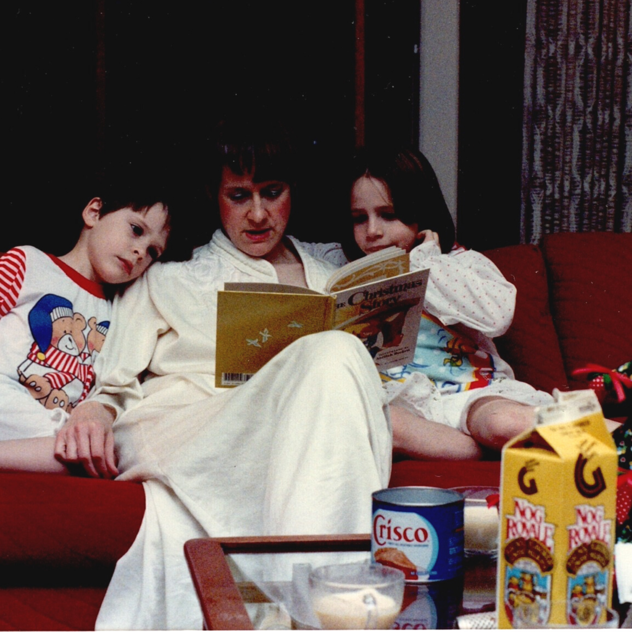 a mother reading Christmas books to her two kids
