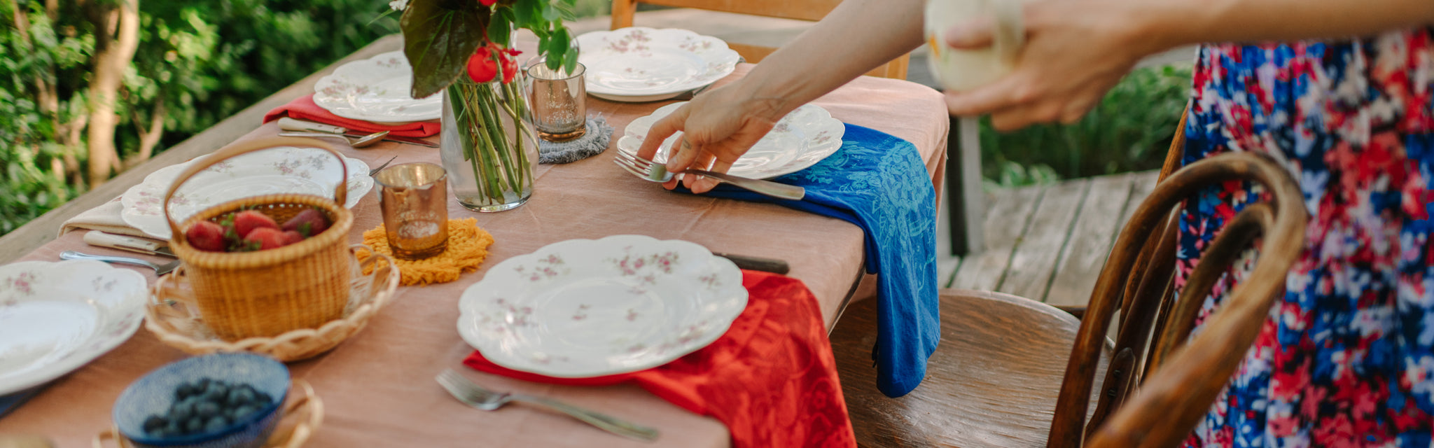 a woman setting a beautiful holiday table with screen printed linens and flowers