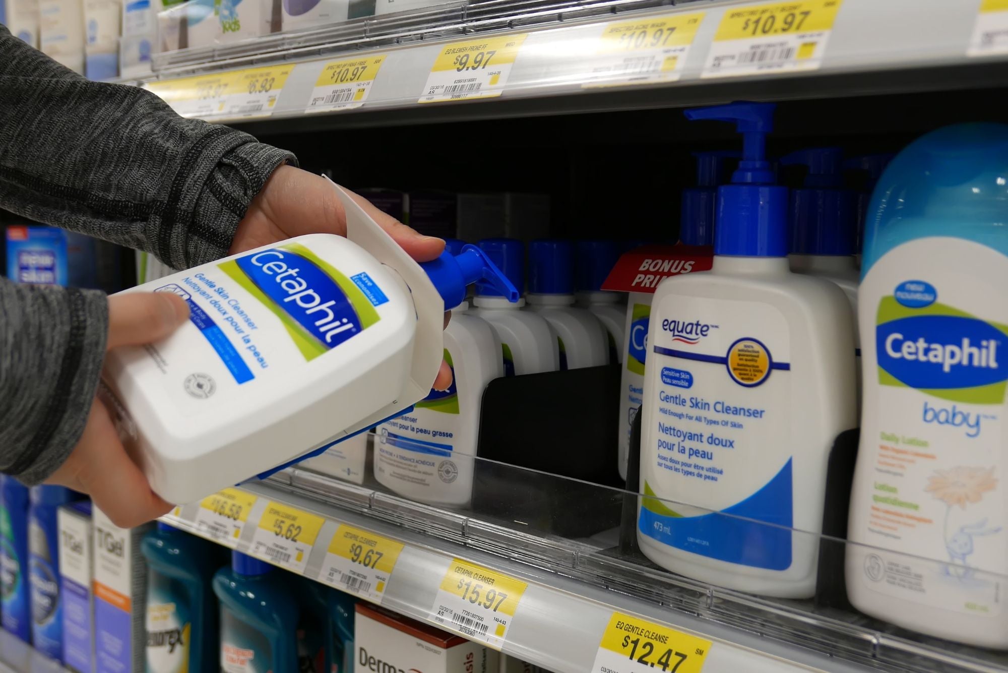 A person picking up Cetaphil from a grocery store shelf, wondering if it will be good for their acne.
