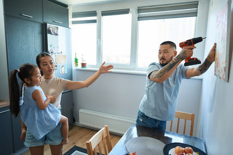 Une famille asiatique en train d'accrocher un tableau personnalisé dans la maison