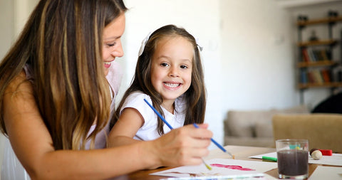 Petite fille en train de peindre avec sa maman