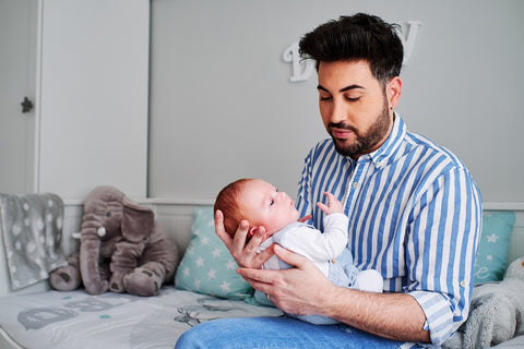 Papa die een pasgeborene in zijn armen houdt - gepersonaliseerde geboortehoroscoop