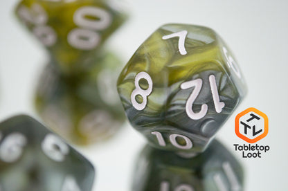 A close up of the D12 from the Disintegrate 7 piece dice set from Tabletop Loot with swirls of silver and gold and white numbering.