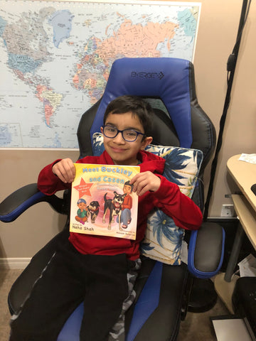 Boy sitting on a chair holding a copy of "Meet Buckley and Casen"