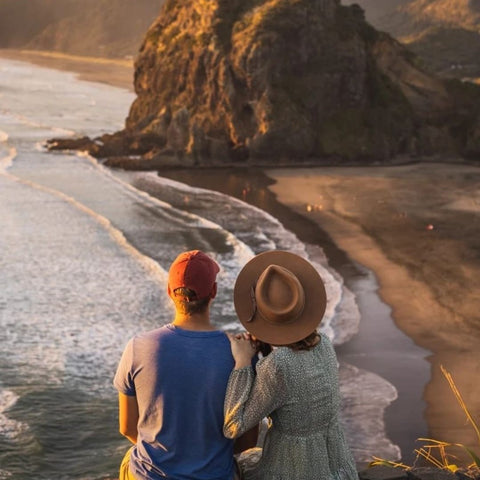 Couple sitting on a cliff enjoying the view of the beach