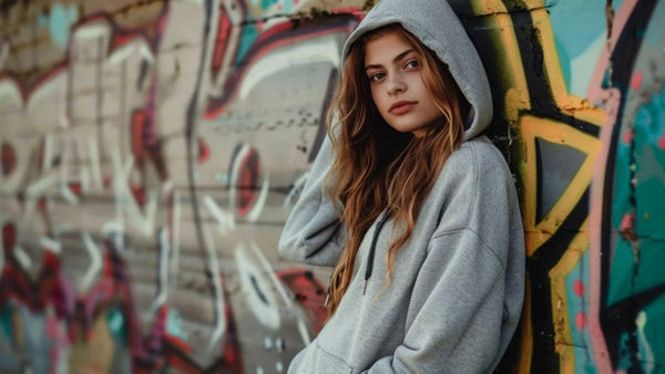 Jeune fille portant hoodie oversize devant mur de street art