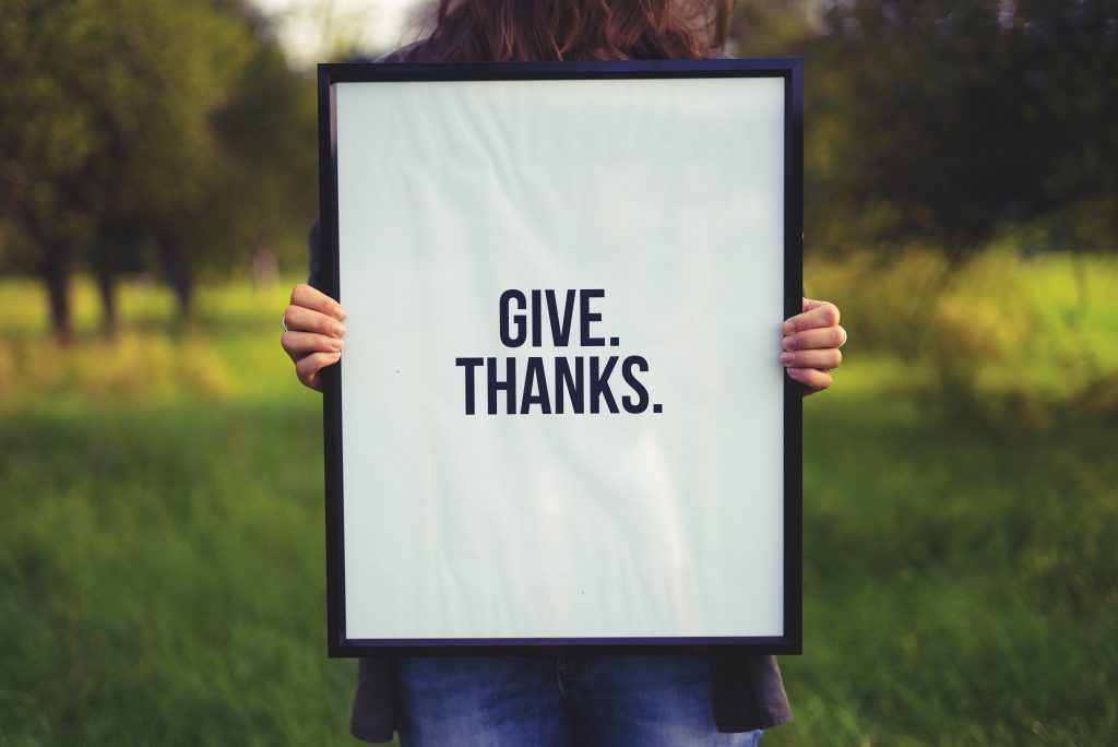 a girl holding a sign that says "give thanks"
